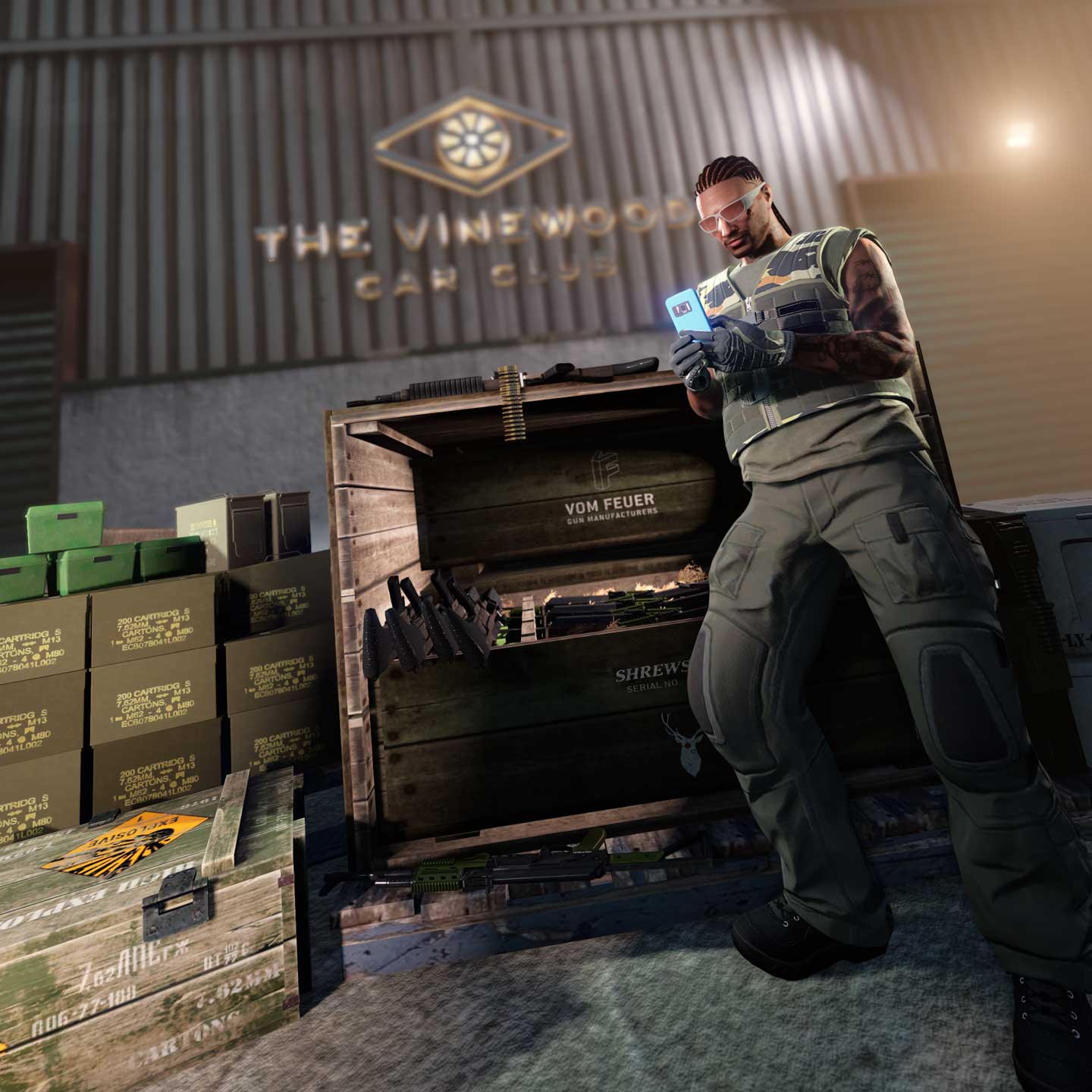 一位 GTA 在线模式角色手持手机，倚靠在堆满武器的箱子旁，背景是好麦坞车友俱乐部。